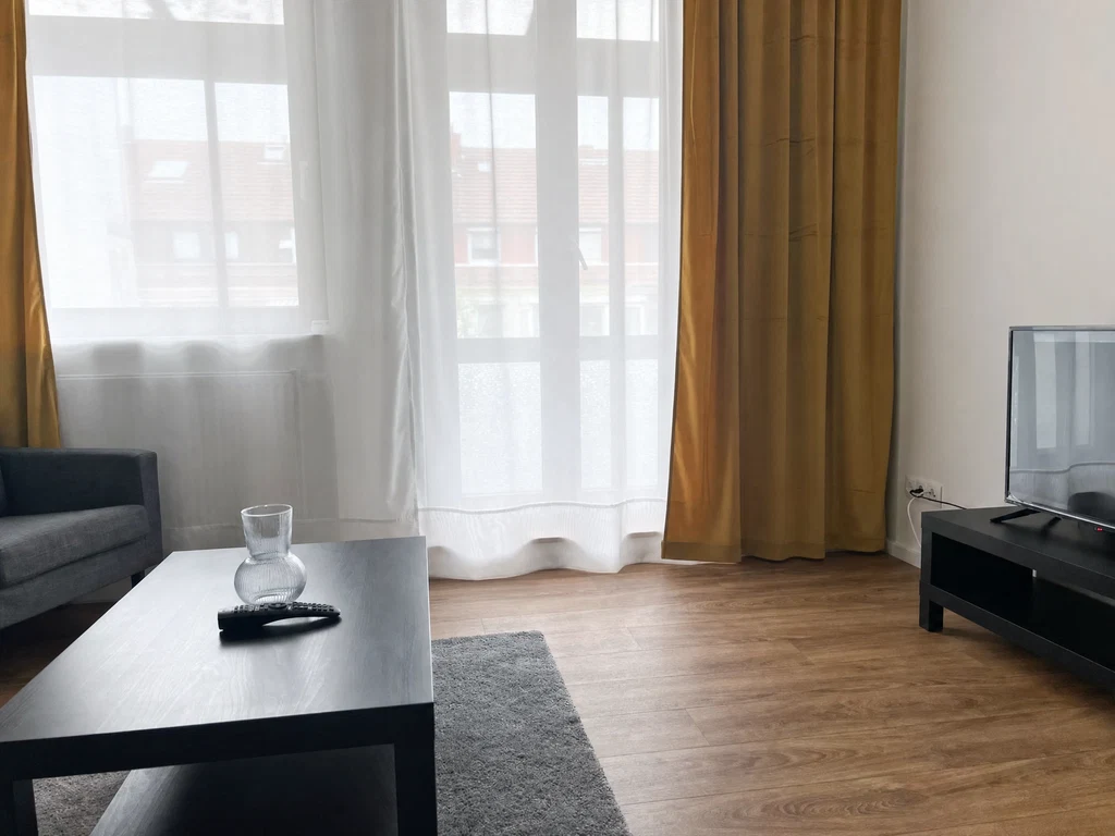 Wohnzimmer mit Sofa, Tisch und Fernseher – Living Time